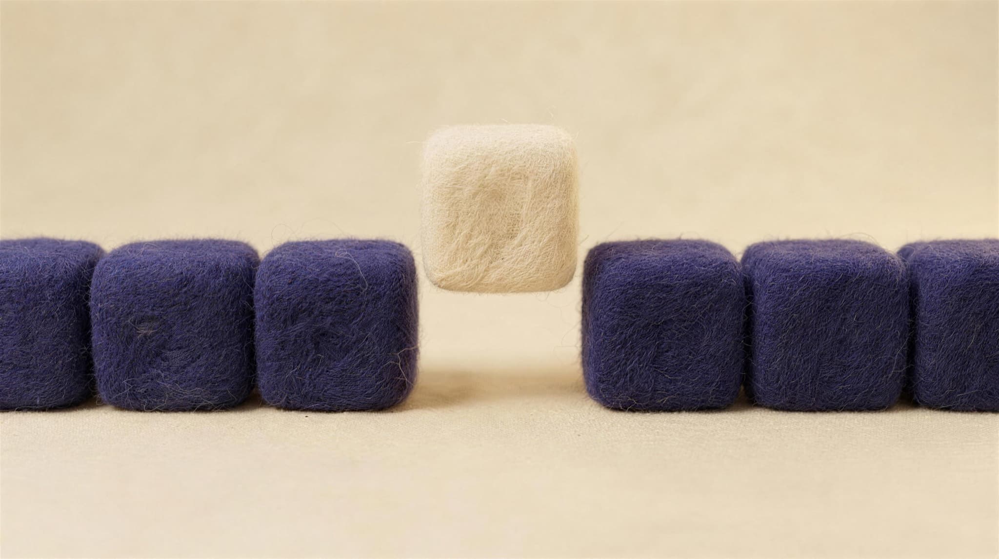 A cream felt block slotting into a row of indigo blocks
