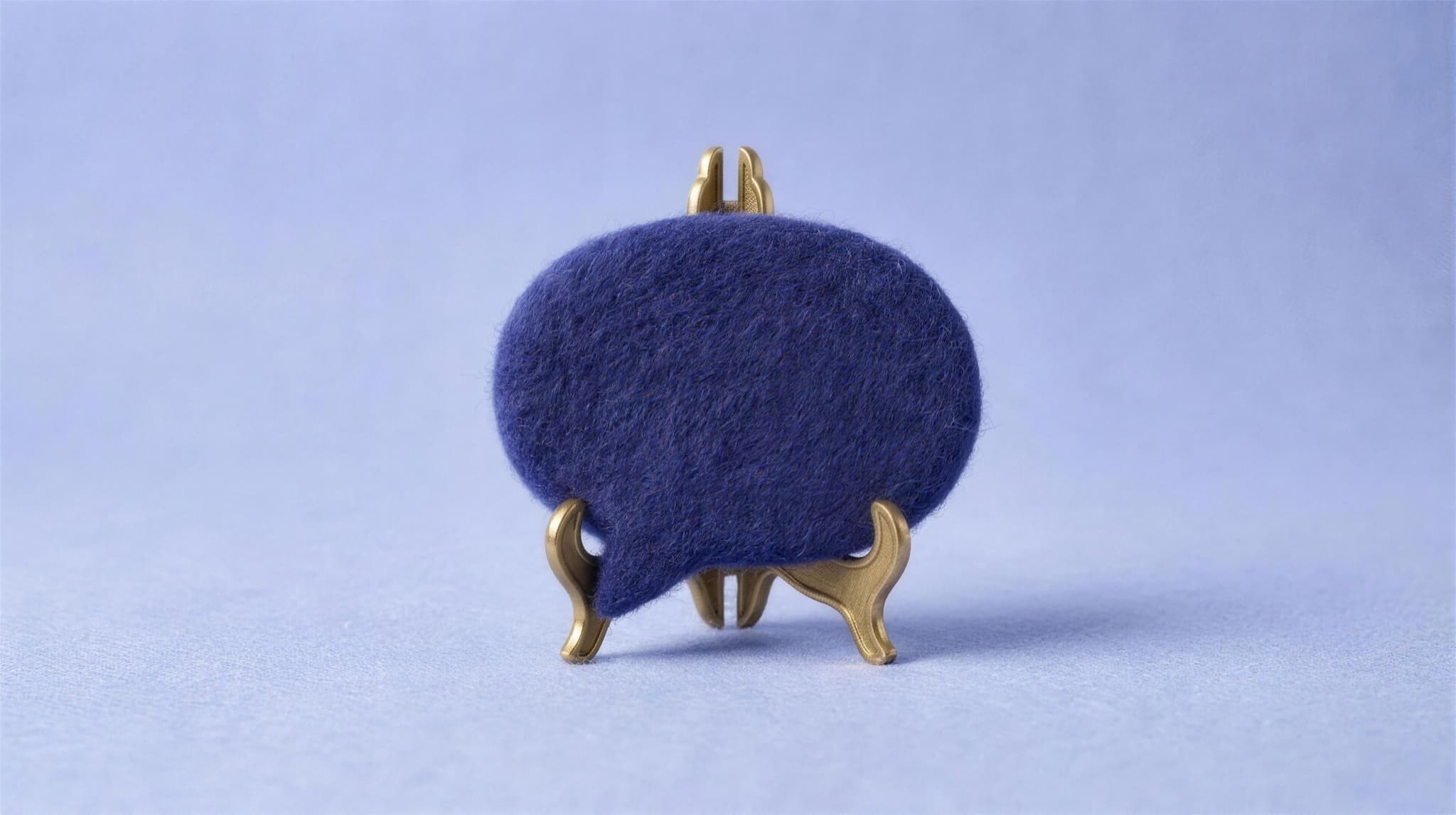 An indigo felt speech bubble displayed on a small brass stand
