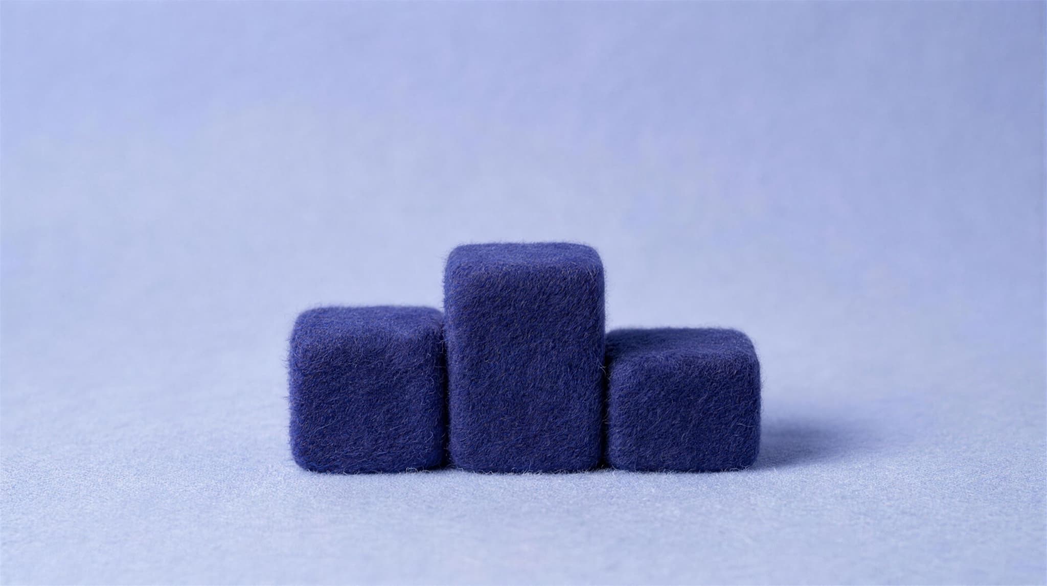 Three indigo felt cubes stacked into a small podium